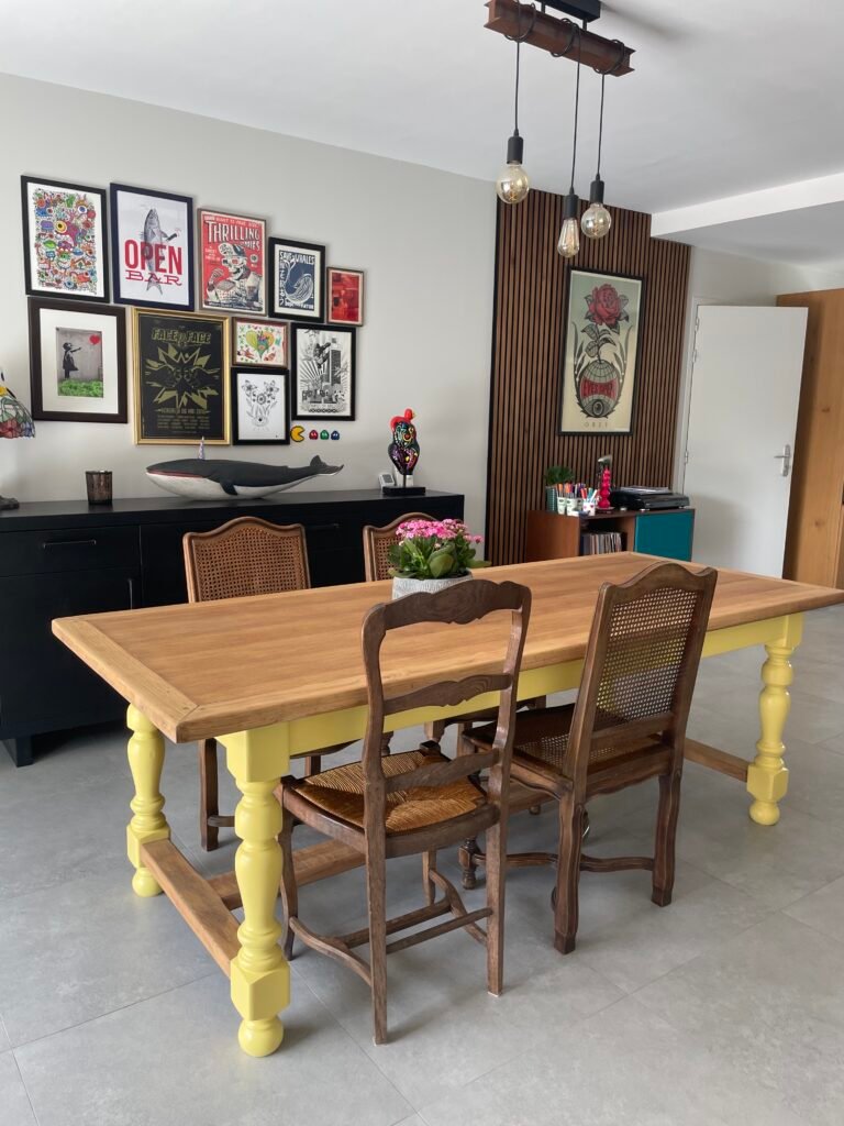 Une table de ferme dans une salle à manger, rénovée en bois clair et jaune poussin sur les pieds
